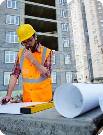 Construction worker reviewing blueprints on site